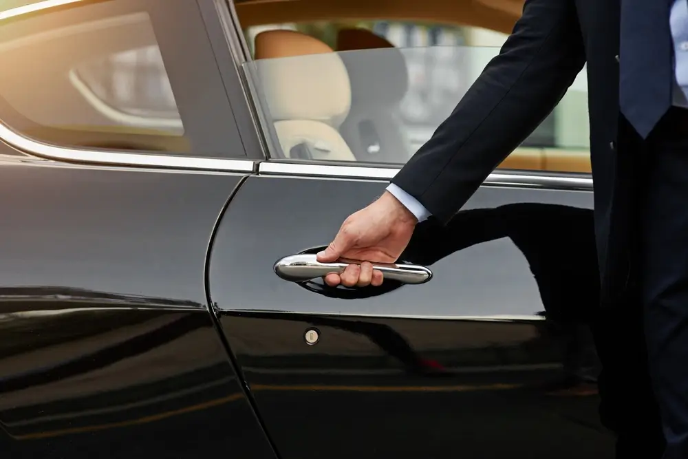 Chauffeur opent de deur van een zwarte wagen